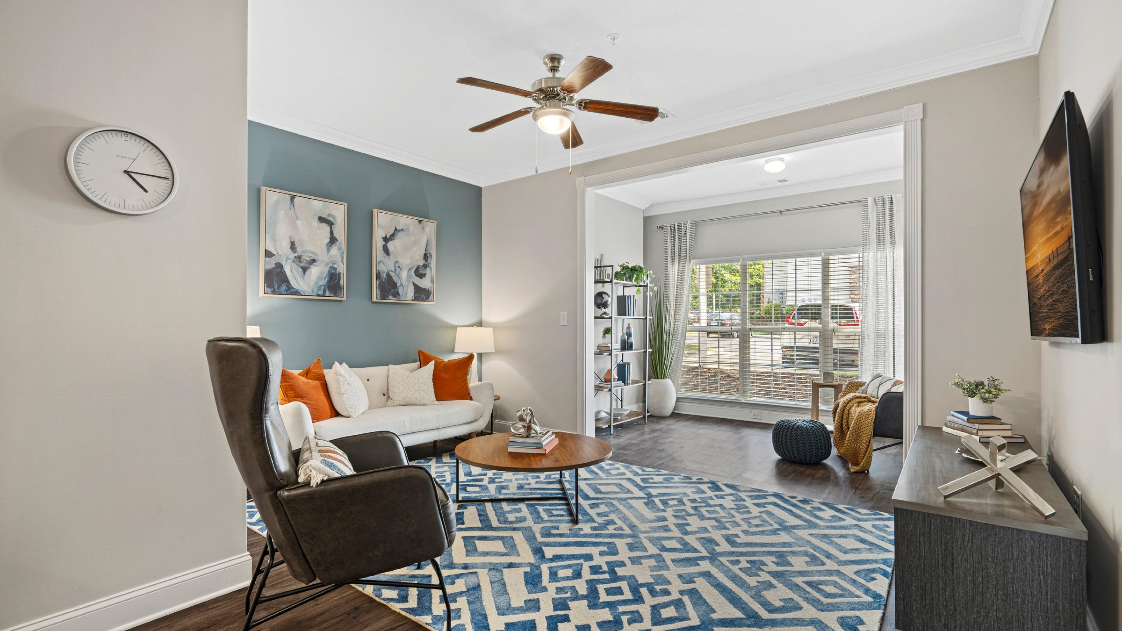 Hawthorne at the Meadows apartment living room with ceiling fan, couch, chair, TV stand, and couch, opening into a small bonus room nook with more space